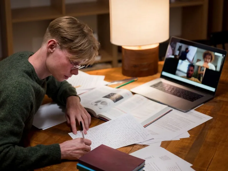 Student at a desk at night working through overdue assignments while keeping up with current coursework.